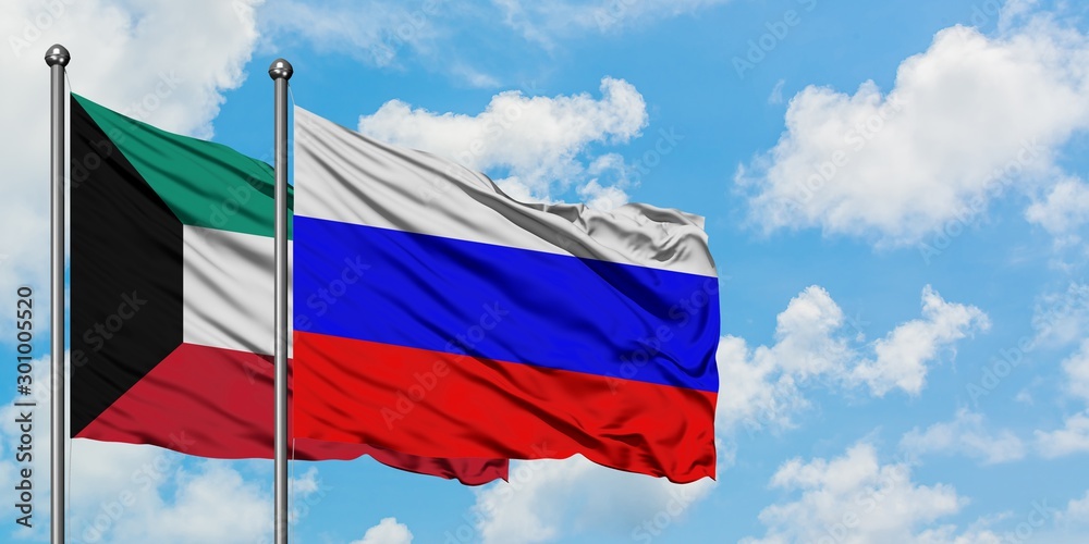 Kuwait and Russia flag waving in the wind against white cloudy blue sky together. Diplomacy concept, international relations.