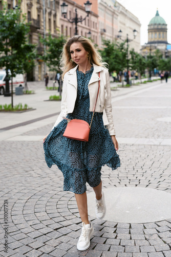 Young blonde hair woman walking on the city street in Saint-Petersburg Russia and smiling. Happy girl having fun outside