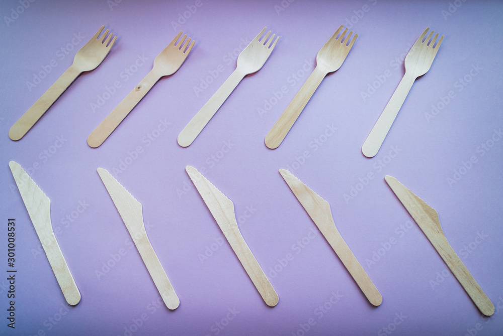 Wooden forks and knives on purple background. Eco friendly concept. Top view. Wooden forks and knives on purple background. Eco friendly concept. Top view.