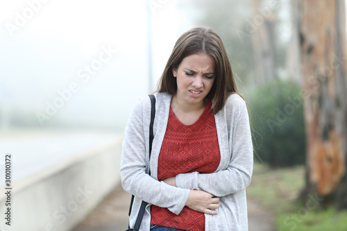 Woman suffering belly ache a foggy day