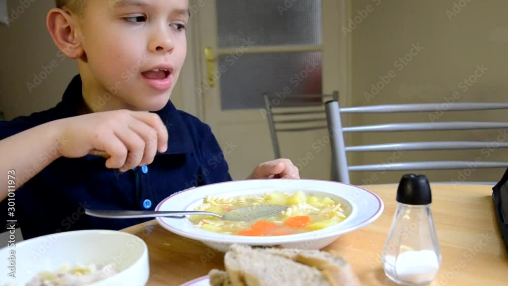 Boy at home in the kitchen eats vegetarian soup with vegetables. Healthy food. Food at home Boy at home in the kitchen eats vegetarian soup with vegetables. Healthy food. Food at home