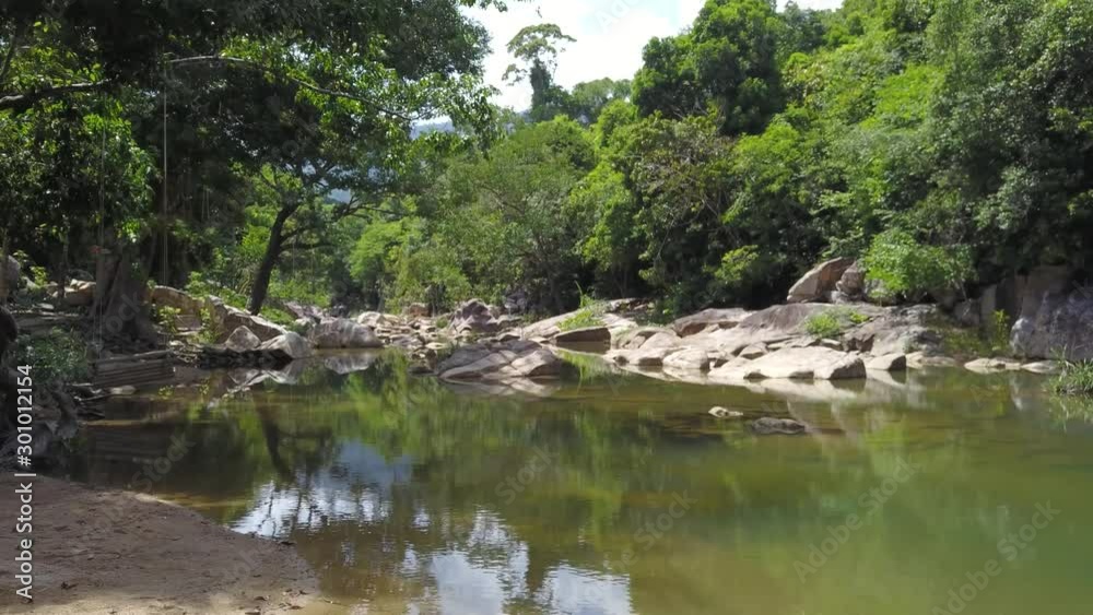 A flying camera flies low over the river overlooking the jungle and large stones in Vietnam. A flying camera flies low over the river overlooking the jungle and large stones in Vietnam.