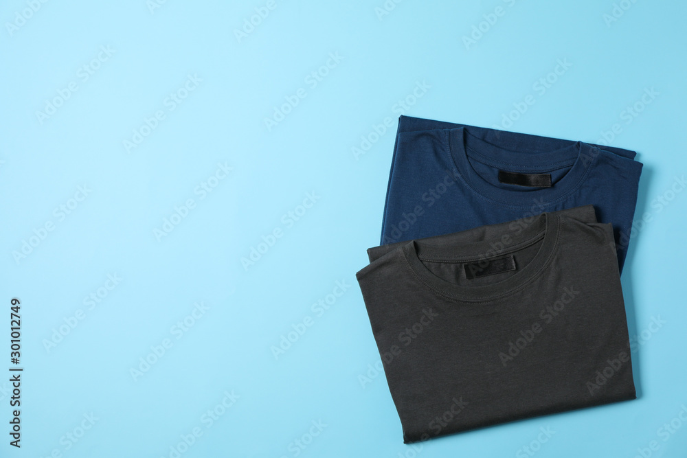 Folded blank t-shirts on blue background, space for text Folded blank t-shirts on blue background, space for text