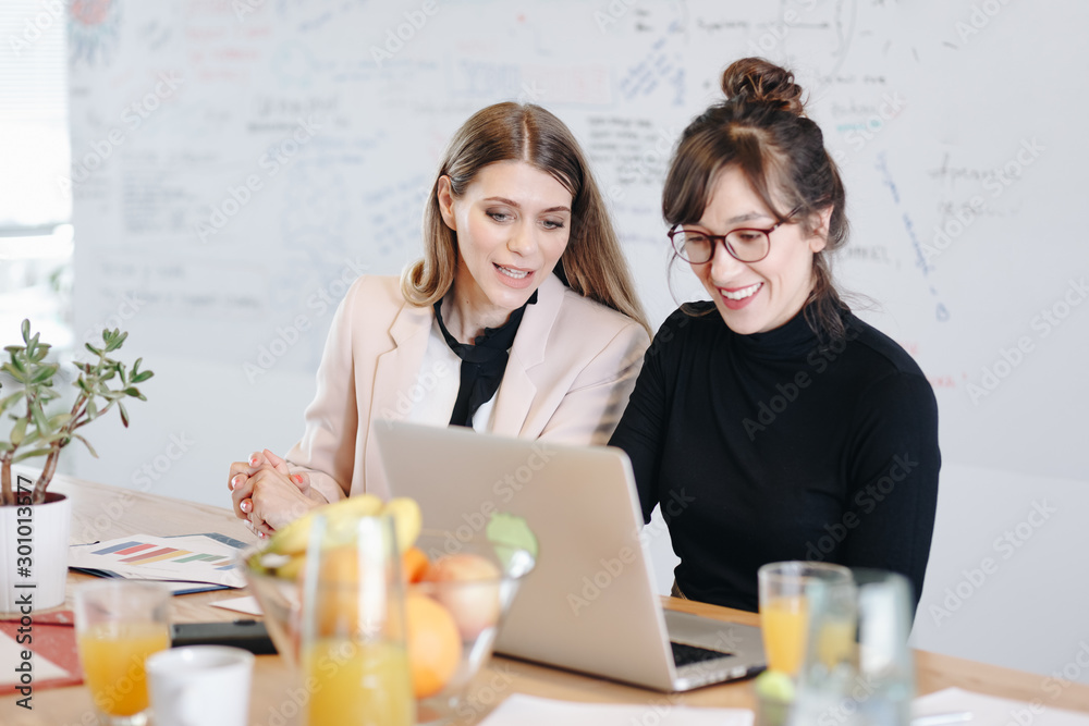 Candid moment, two women working together in modern office interior. Businesswomen collaborating on presentation for a big meeting. Candid moment, two women working together in modern office interior. Businesswomen collaborating on presentation for a big meeting.