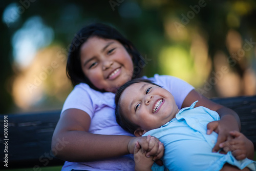 Little brother enjoying the company of his sister as he laughs with a joyful expression and holds her hand.