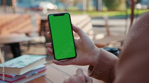 Slow motion hands woman holding use phone with green screen sitting in cafe scrolling pages swiping surfing internet technology smartphone chroma key message close up