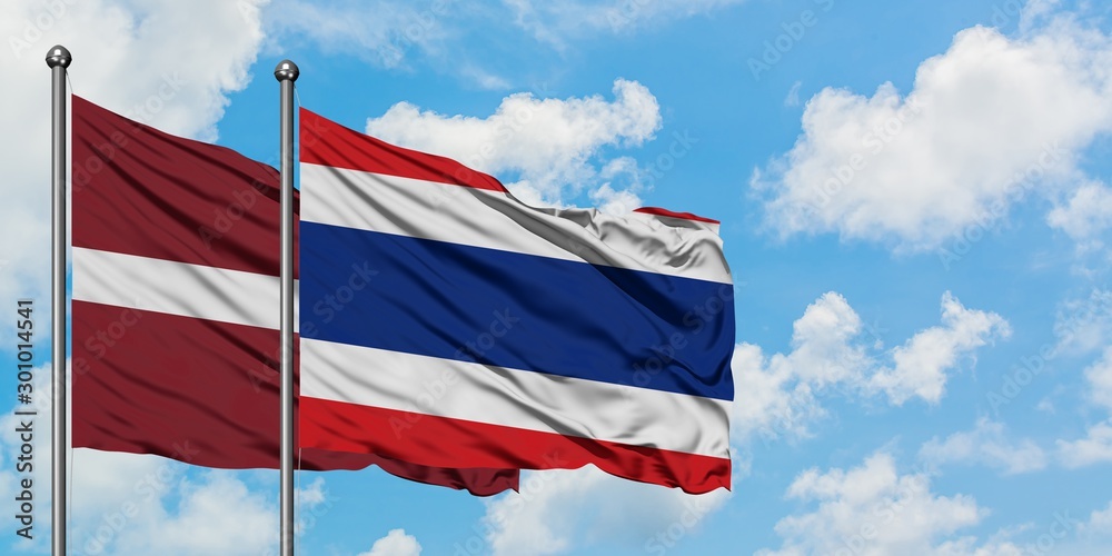 Latvia and Thailand flag waving in the wind against white cloudy blue sky together. Diplomacy concept, international relations.