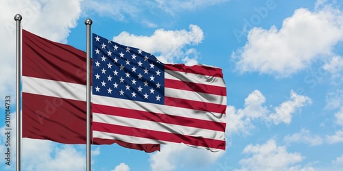 Tableau sur toile Latvia and United States flag waving in the wind against white cloudy blue sky together