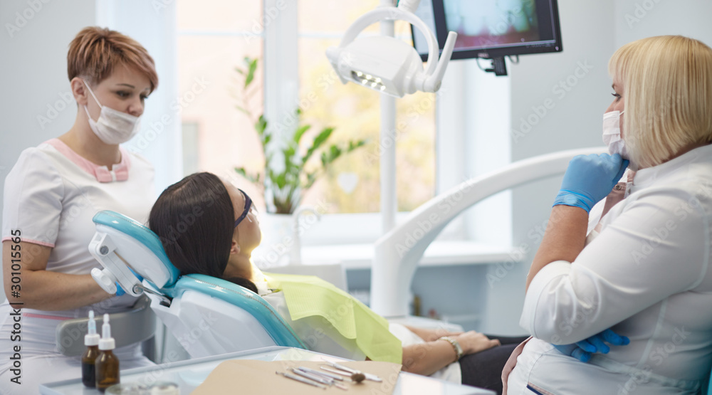 Obraz premium Doctor dentist treats teeth of a beautiful young girl patient. The girl on reception at the dentist. Doctor dentist treats tooth