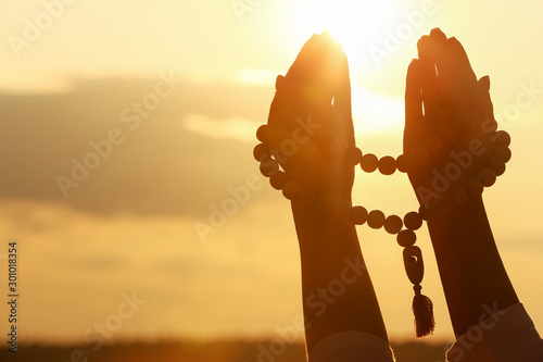 Hands of Muslim woman praying outdoors at sunset