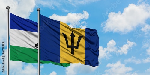 Lesotho and Barbados flag waving in the wind against white cloudy blue sky together. Diplomacy concept, international relations.
