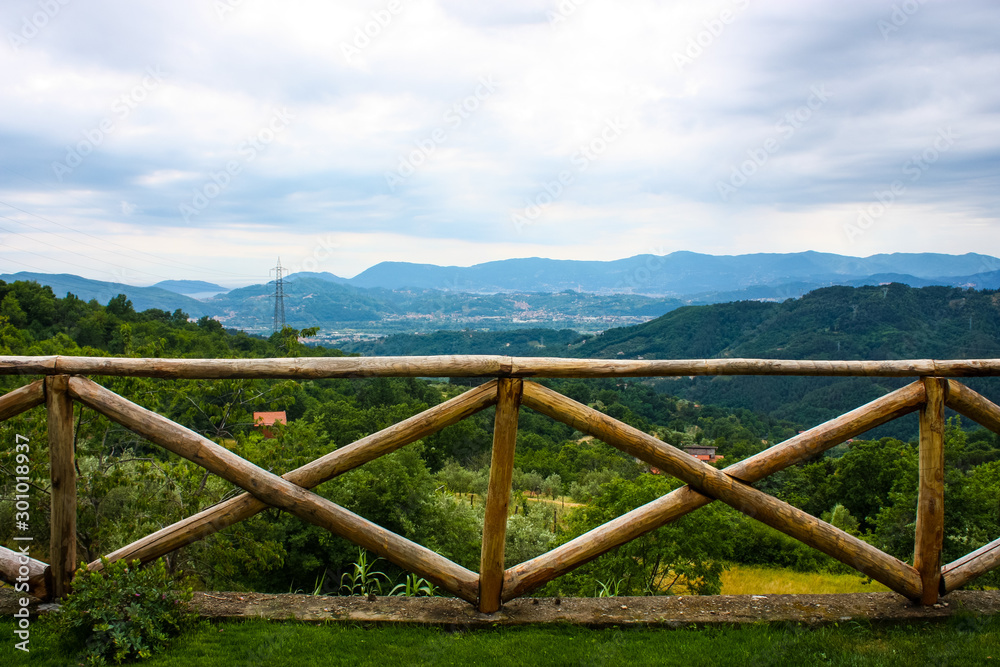 panoramic view of the mountains of liguria behind a wooden fence during a cloudy day