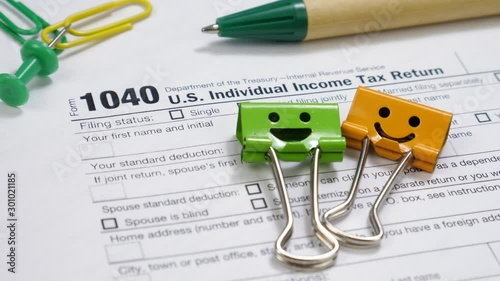Smiles Binder Clips and Pen on 1040 Tax Form. Individual Income tax return document in United States