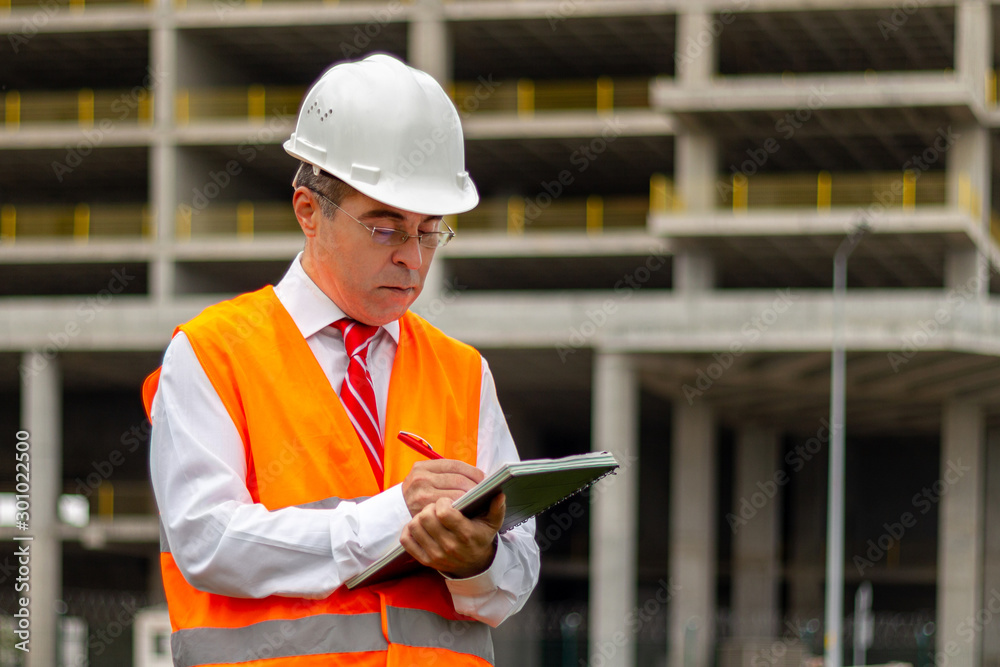 Fototapeta premium Construction engineer man in shirt and tie with safety helmet and vest works at construction site. Concept of people working in industrial field