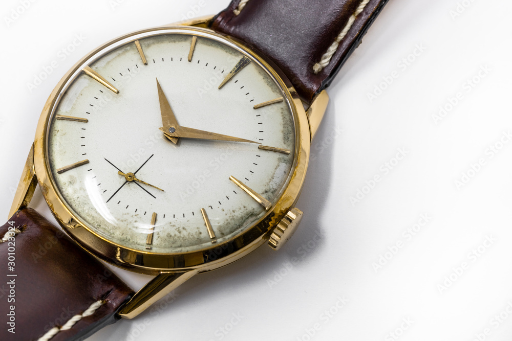 An old gold mechanical wristwatch with manual winding. Antique watch ruined by time, with scratches and mildew stains, rust, oxidation. Leather strap (band). Vintage clock. Spend time. An old gold mechanical wristwatch with manual winding. Antique watch ruined by time, with scratches and mildew stains, rust, oxidation. Leather strap (band). Vintage clock. Spend time.