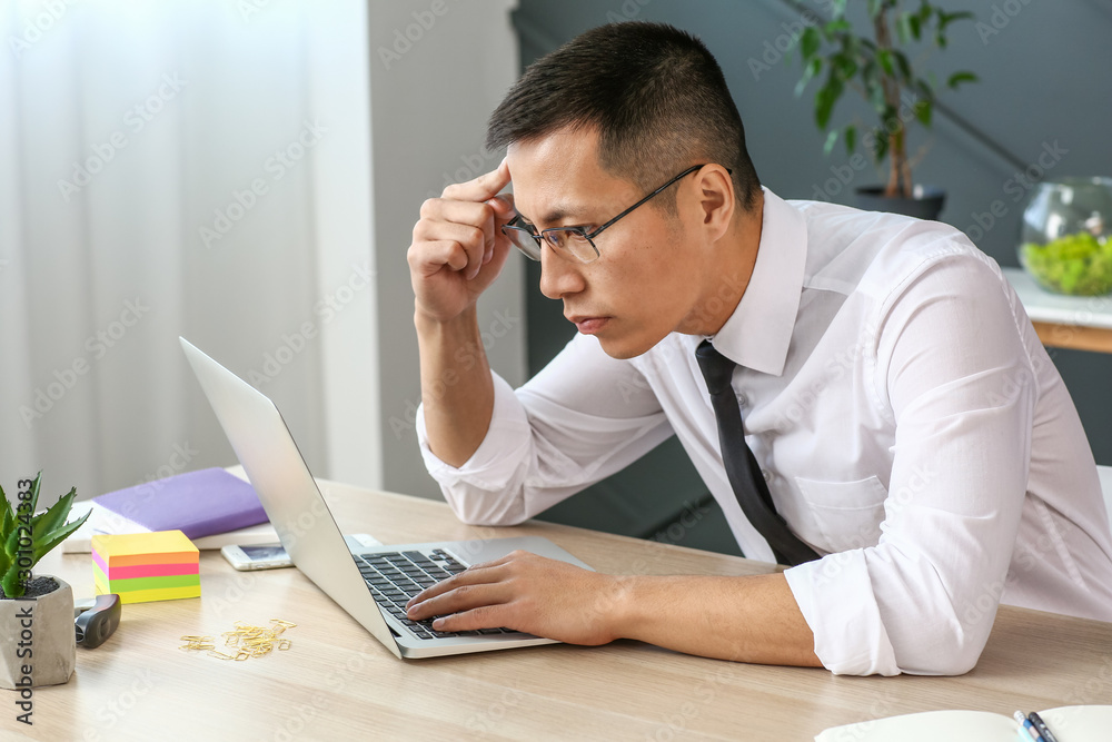 Asian businessman working on laptop in office Asian businessman working on laptop in office