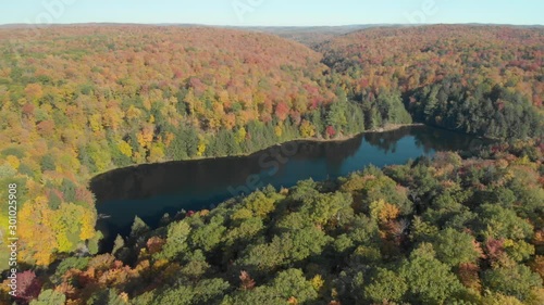 Beautiful drone footage rising over the peaks of the Gatineau Park Hills in Quebec and revealing an amazing autumn landscape surrounding Lake Meech near The Carbide Willson Ruins. photo
