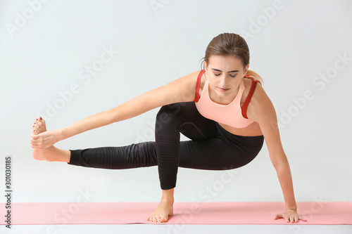 Beautiful young woman practicing yoga on light background