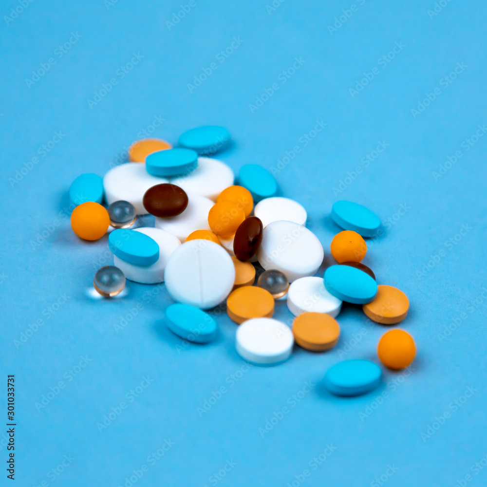 Multi-colored pills on a blue background close-up, with copy space for text