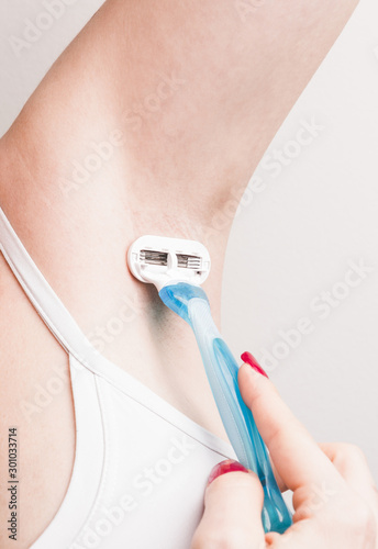 Close up of hand woman shaves armpit disposable razor. Armpit's care concept.