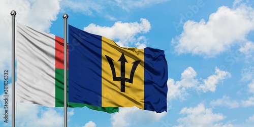 Madagascar and Barbados flag waving in the wind against white cloudy blue sky together. Diplomacy concept, international relations.
