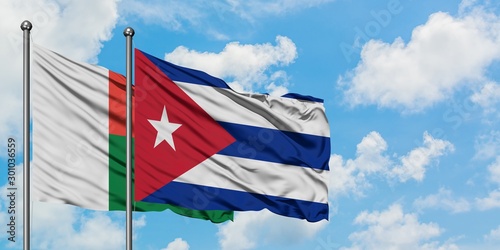 Madagascar and Cuba flag waving in the wind against white cloudy blue sky together. Diplomacy concept, international relations.