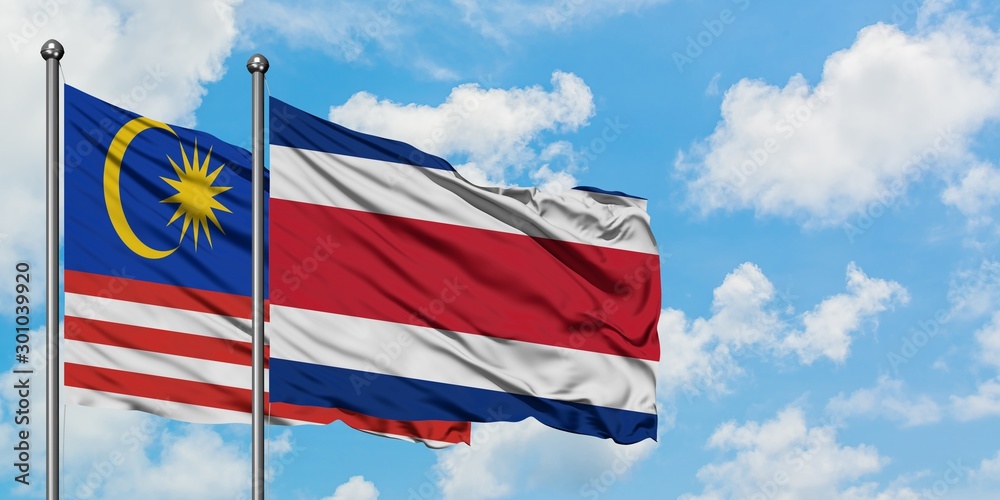 Malaysia and Costa Rica flag waving in the wind against white cloudy blue sky together. Diplomacy concept, international relations.