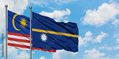 Malaysia and Nauru flag waving in the wind against white cloudy blue sky together. Diplomacy concept, international relations.
