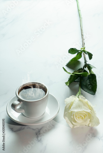 coffee background of a cup of hot black coffee with bunch of white rose on white marble background