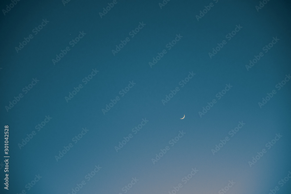 Small crescent moon and a tiny star in a vast evening sky. Small crescent moon and a tiny star in a vast evening sky.