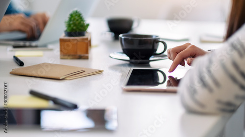 A woman using and pointing finger at a tablet pc with coffee cup on the table