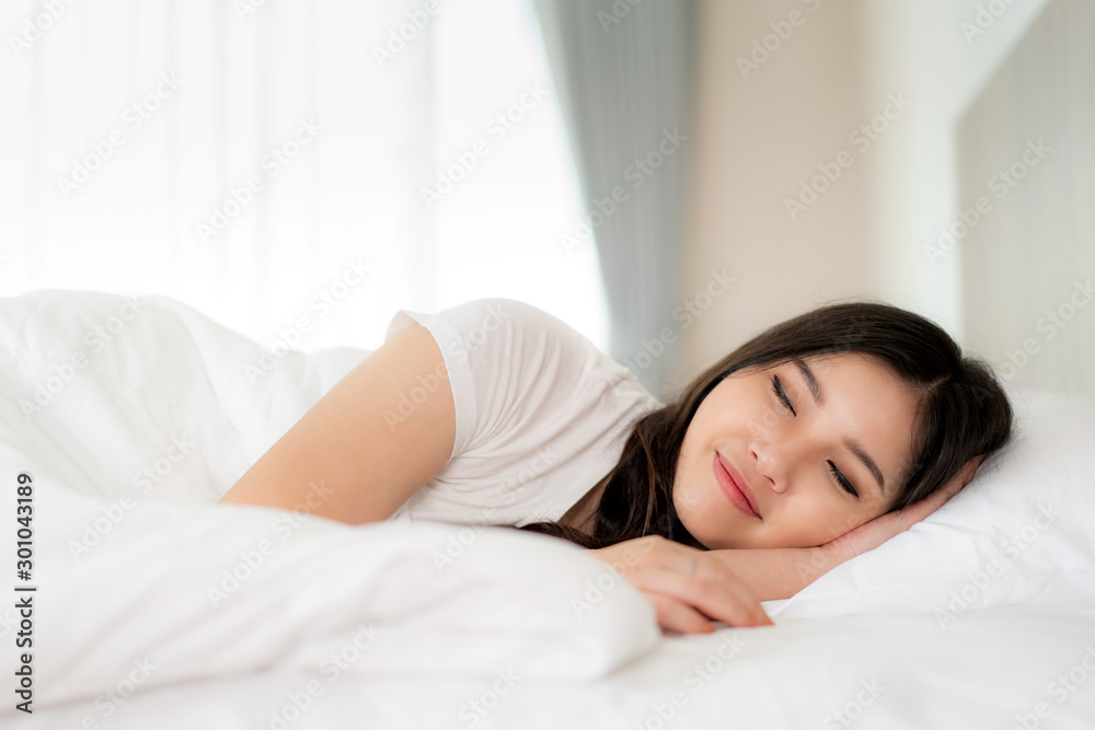 Portrait of beautiful Asian woman with attractive smile enjoy fresh soft bedding linen mattress in white bed room modern apartment. Cute asia girl sleep resting, good night sleep concept.. Portrait of beautiful Asian woman with attractive smile enjoy fresh soft bedding linen mattress in white bed room modern apartment. Cute asia girl sleep resting, good night sleep concept..
