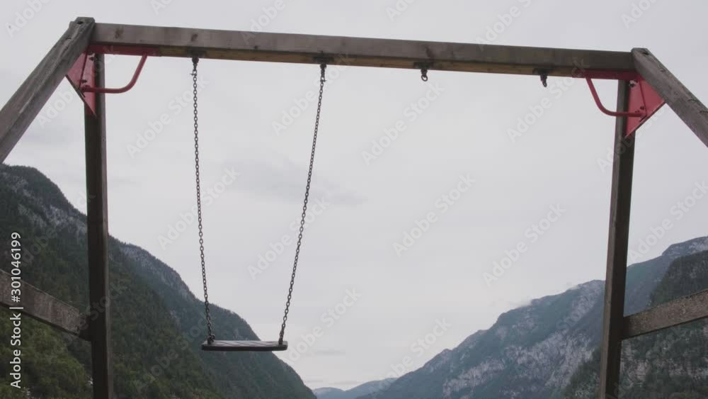 A empty children's swings at a playground on a overcast day.