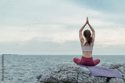 The back of the woman doing yoga Sit in a workout position, sit posture, easy posture, amazing yoga style in a beautiful view and enjoy the evening sea view. Concept for exercise, health care.