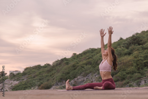 Young women practicing yoga and practicing yoga postures Amazing yoga landscape in the beautiful sky and enjoying the sea view on the wood floor, ideas for exercise, health care