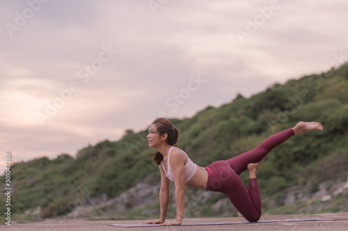 Young women practicing yoga and practicing yoga postures Amazing yoga landscape in the beautiful sky and enjoying the sea view on the wood floor, ideas for exercise, health care