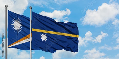 Marshall Islands and Nauru flag waving in the wind against white cloudy blue sky together. Diplomacy concept, international relations.