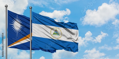 Marshall Islands and Nicaragua flag waving in the wind against white cloudy blue sky together. Diplomacy concept, international relations.