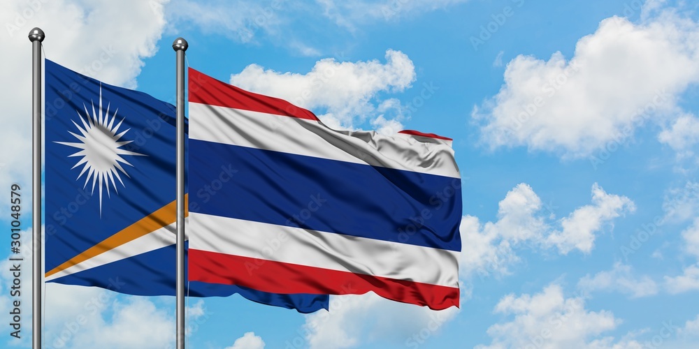 Marshall Islands and Thailand flag waving in the wind against white cloudy blue sky together. Diplomacy concept, international relations.