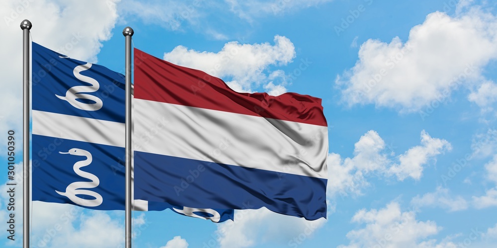 Martinique and Netherlands flag waving in the wind against white cloudy blue sky together. Diplomacy concept, international relations.