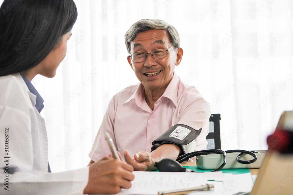 Obraz premium Doctor measuring blood pressure of elderly man in medical office.