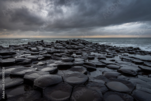 The natural hexagonal stones at the coast called Giant's Causeway, a landmark in Northern Ireland with dramatic cloudy sky. photo