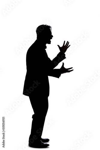 Silhouette of a backlit model posing as a businessman on a white background.  He is shouting in anger and is furious photo