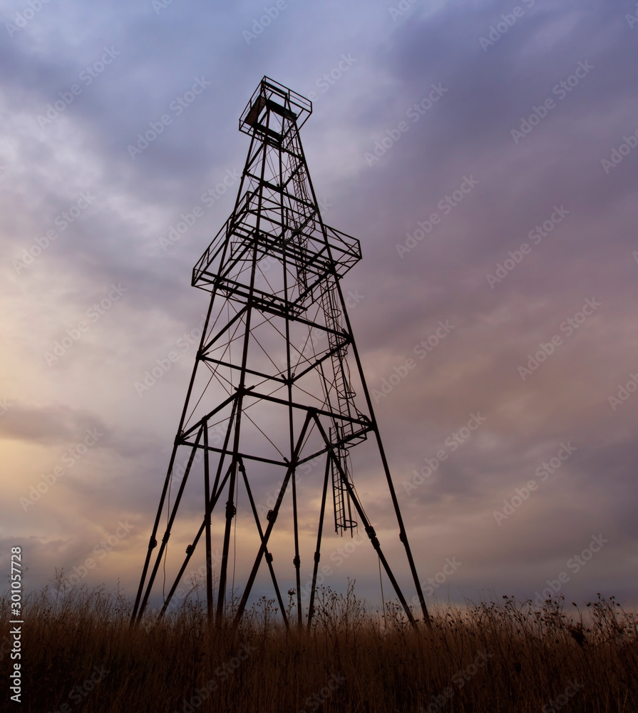 Old oil rig, profiled on sky with storm clouds, at sunset Old oil rig, profiled on sky with storm clouds, at sunset