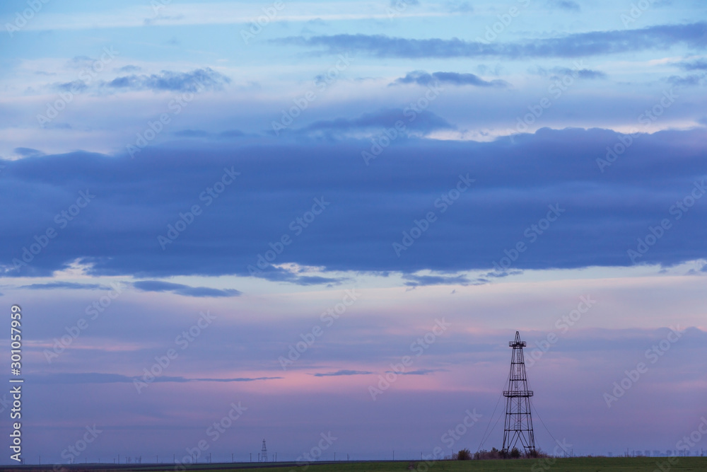 Abandoned oil rig in a field in Eastern Europe,. profiled on background with sunset storm clouds