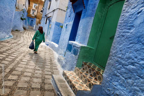 A traditional dressed moroccan woman walks in the old town (medina) of Chefchaouen in Morocco.