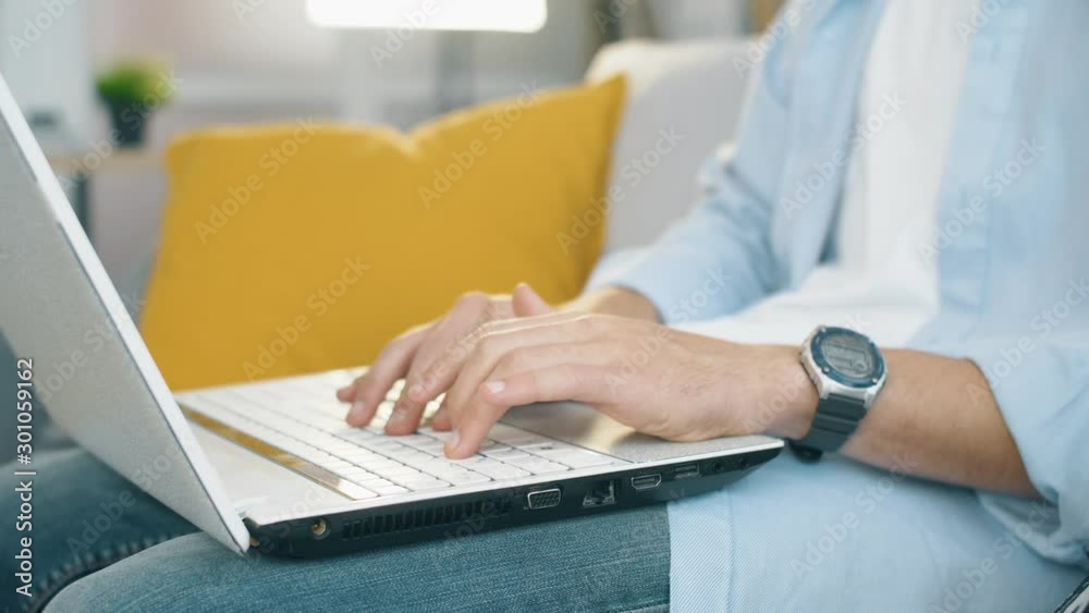 Freelancer seat on sofa in modern living room and typing on laptop keyboard. Close up 4k slow motion footage. Freelancer seat on sofa in modern living room and typing on laptop keyboard. Close up 4k slow motion footage.