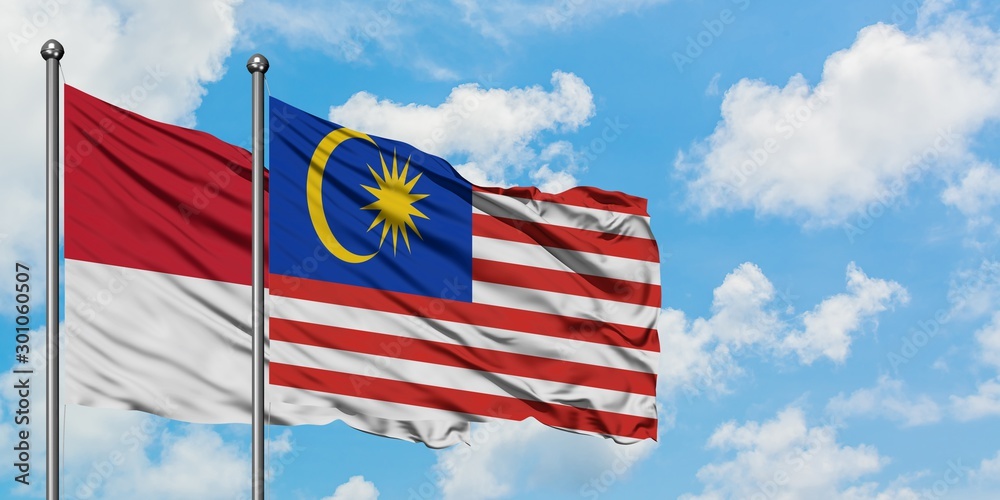 Monaco and Malaysia flag waving in the wind against white cloudy blue sky together. Diplomacy concept, international relations. Monaco and Malaysia flag waving in the wind against white cloudy blue sky together. Diplomacy concept, international relations.