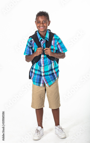 Smiling African American school boy isolated on white background. Wearing a backpack and a plaid shirt and ready to go to school. Front view