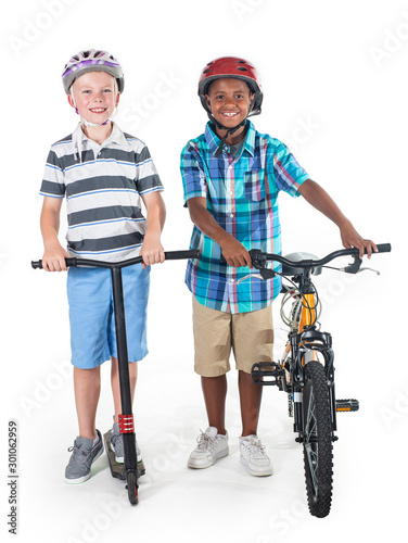 Two smiling diverse schoolboys isolated on a white background. Full length photo of the boys On their way to school riding a bike and a scooter. Education concept photo
